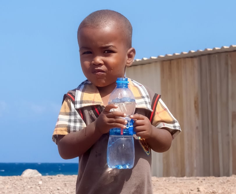 Child holding a water bottle, representing the impact of water charity
