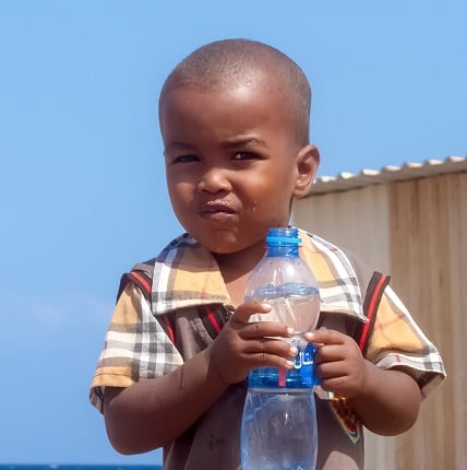 Child holding a water bottle, representing the impact of water charity