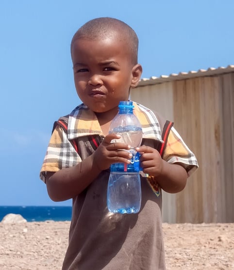 Child holding a water bottle, representing the impact of water charity